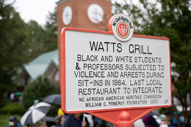 NC Civil Rights Trail sign that says "Watts Grill: Black and white students & professors subjected to violence and arrests during sit-ins in 1964. Last local restaurant to integrate. NC African American Heritage Commission William C Pomery Foundation 2023"